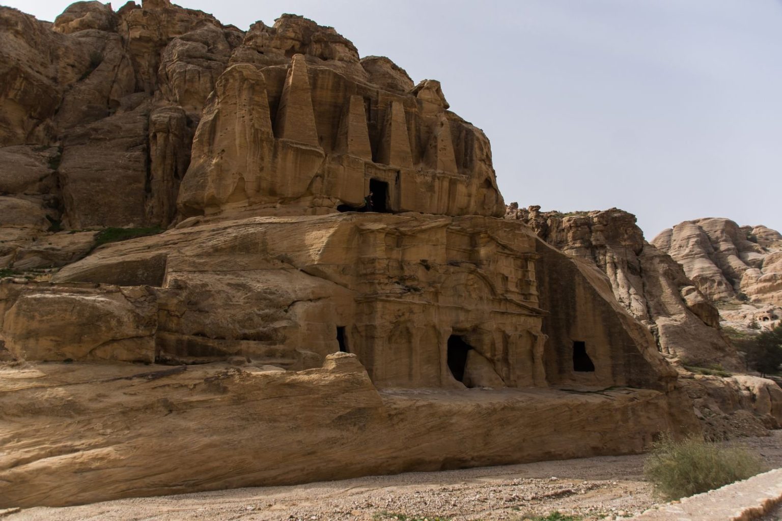 An ancient rock-cut tomb in a rugged desert landscape