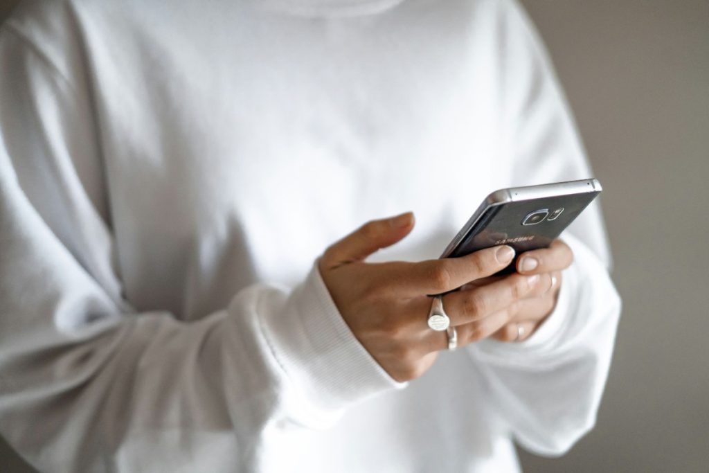 From panic spending to planned repayments: regaining control of household budgets: a person in a white jumper checking their household budget on a mobile phone