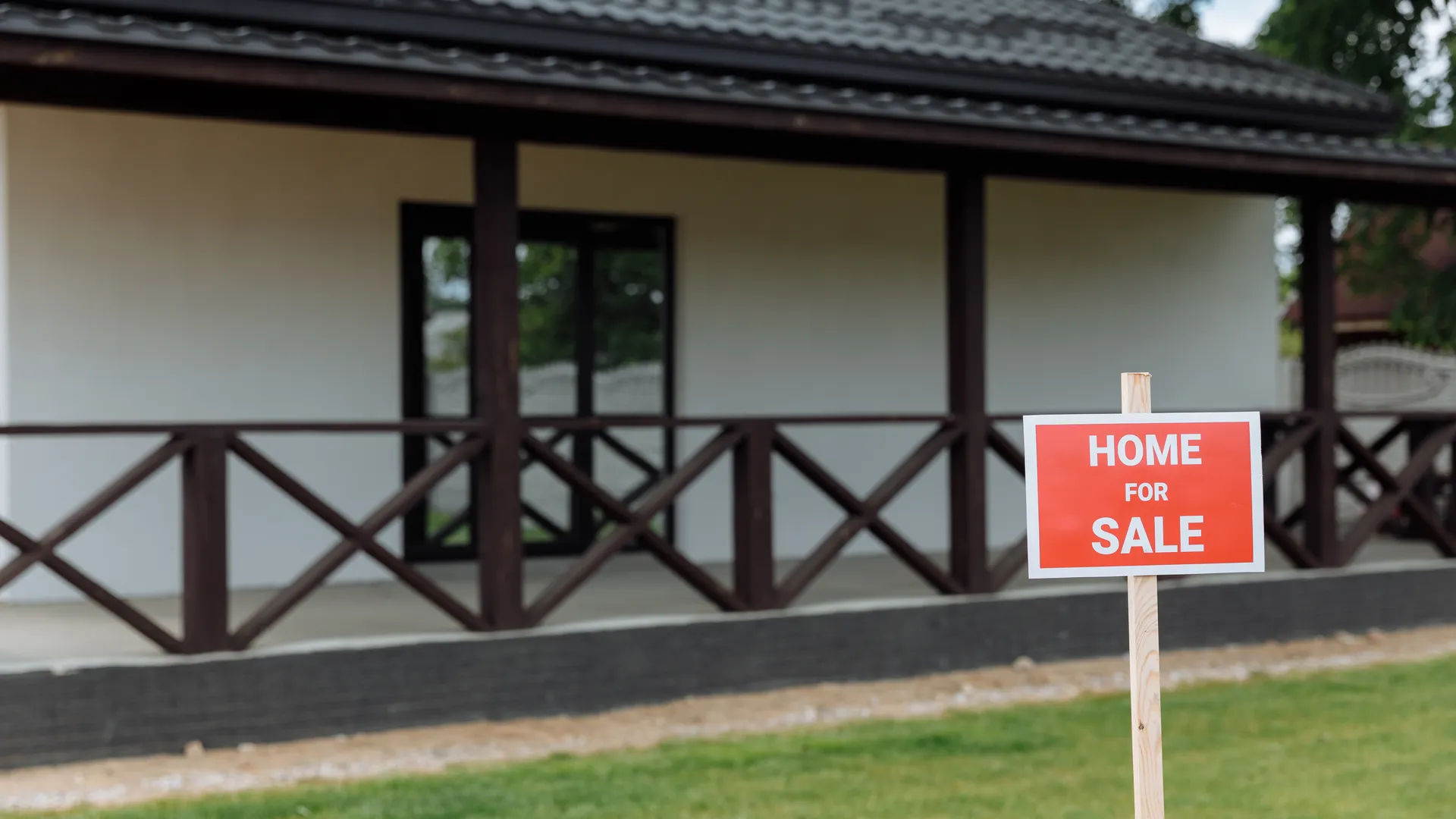 Home for sale sign outside a house with a porch