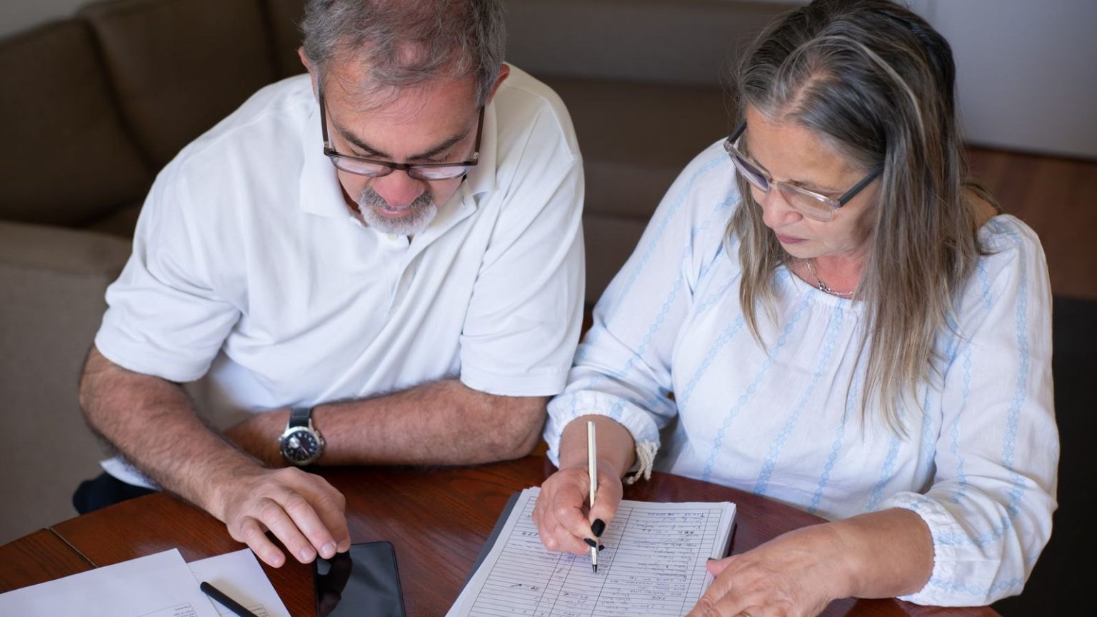 Rushing to take tax-free pension cash can backfire in later years Rushing to take tax-free pension cash can backfire in later years: an older couple going through pension and retirement paperwork together at home