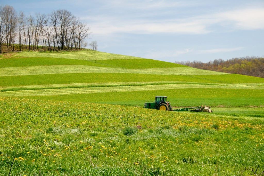 Tractor working a rolling green field on a farm