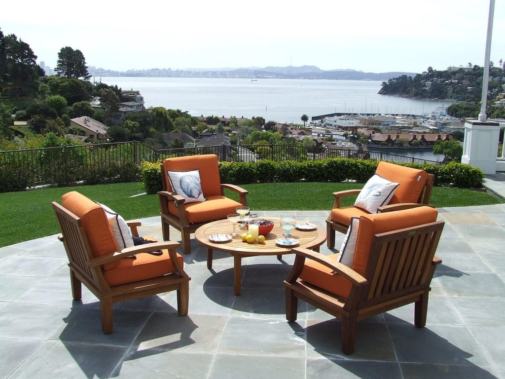 Built for Summers, Not Seasons: Why a Wooden Sun Lounger Outlasts the Cheap Alternatives Wooden patio chairs and table on a terrace overlooking the sea